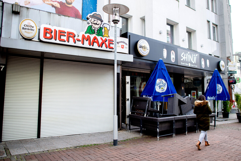 Eine Passantin geht an einer geschlossenen Kneipe und einer Sushi-Bar vorbei. (Symbolbild)
