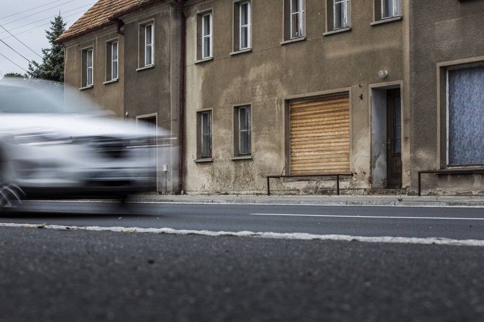 Ein Auto fährt an einem verlassenen Haus vorbei - in Sachsens Landkreisen wird das fortan häufiger vorkommen. (Symbolfoto)