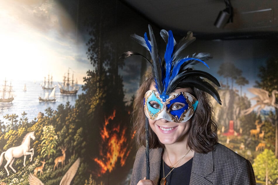 Gästebetreuerin Anja Rossignoli (26) posiert mit einer venezianischen Maske vor dem XXL-Bild, das Casanovas utopischen Roman visualisiert.