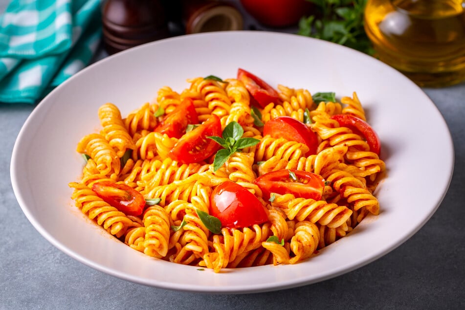 Geviertelte kleine Tomaten und ein paar Blätter Basilikum vollenden die Tomatensoße.