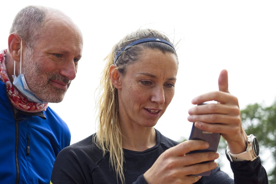 President of the National Paralympic Committee and Paralympic athlete Marie-Amelie Le Fur (r.) looks at her mobile phone next to her mental coach and osteopath, Matthieu Benoît (l.) during a training session on May 21, 2021 at the Jean-Leroy stadium of Blois, Center France.