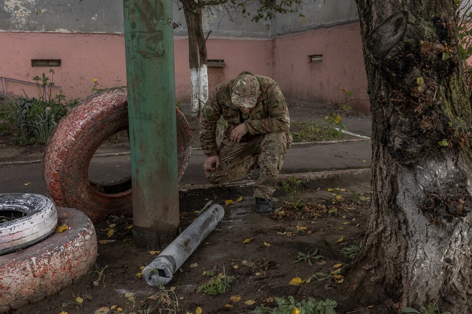 A man in a military uniform looks at a part of a missile next to a residential building that was damaged during an overnight Russian attack, in the southern city of Kherson, on October 30, 2023, amid the Russian invasion of Ukraine.