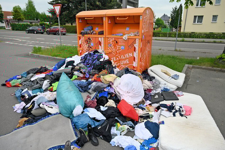 Auf der Hans-Weigel-Straße liegen zahlreiche Klamotten vor den Behältern.