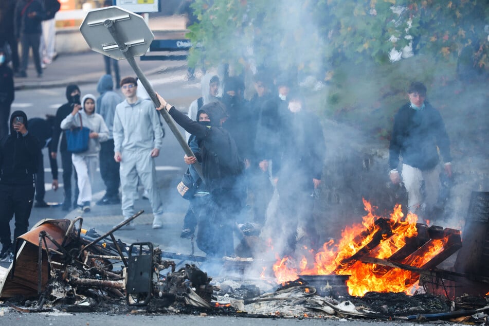 Ein Demonstrant wirft ein Stoppschild in ein Feuer, während protestierende Schüler in der Nähe des Gymnasiums Kerichen im westfranzösischen Brest Blockadeaktionen durchführen.