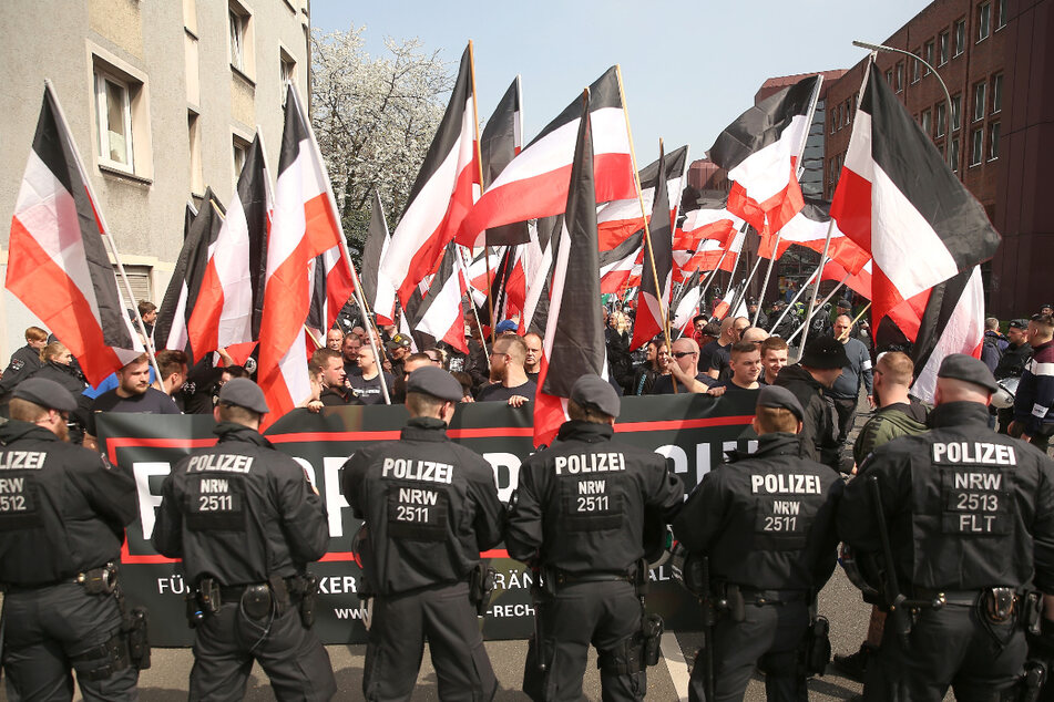 Polizisten stehen vor fahnenschwenkenden Demonstranten bei einer Demonstration von Rechtsextremisten in der Dortmunder Innenstadt.