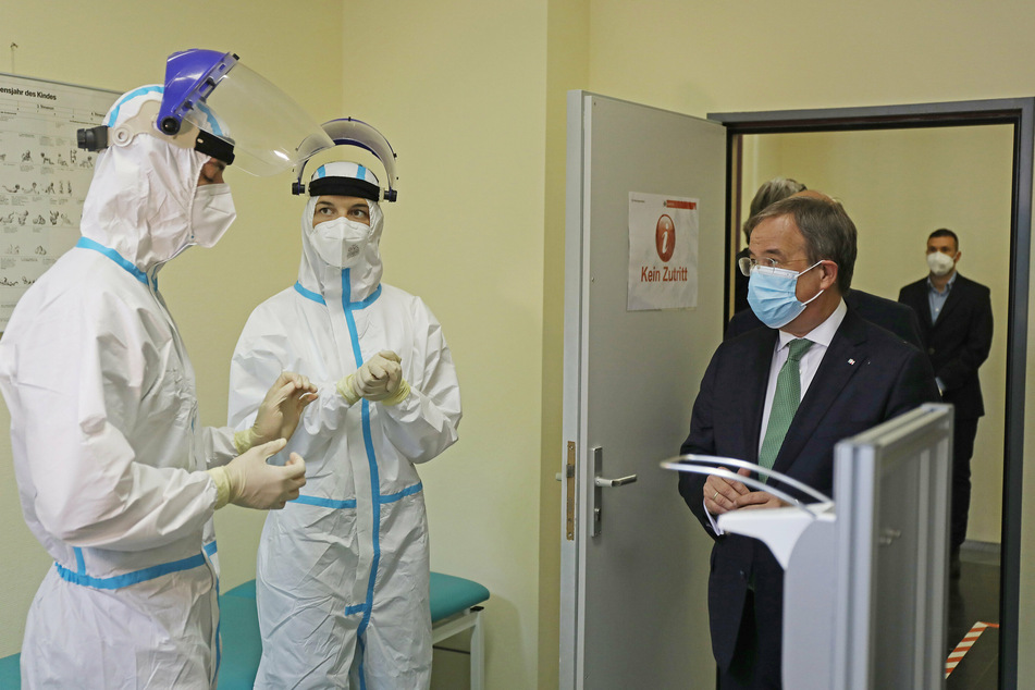 Armin Laschet, NRWs Ministerpräsident (r, CDU), spricht im Gesundheitsamt Köln mit Mitarbeitern in einem Testraum für Abstriche.