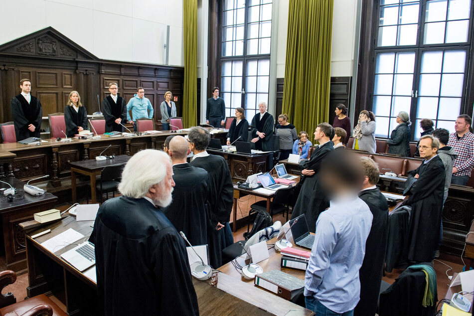 Die Angeklagten stehen mit ihren Anwälten im Landgericht im Saal.