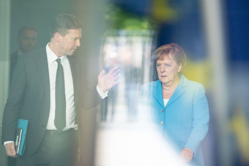 Regierungssprecher Steffen Seibert geht neben Bundeskanzlerin Angela Merkel (CDU) durch das Bundeskanzleramt.