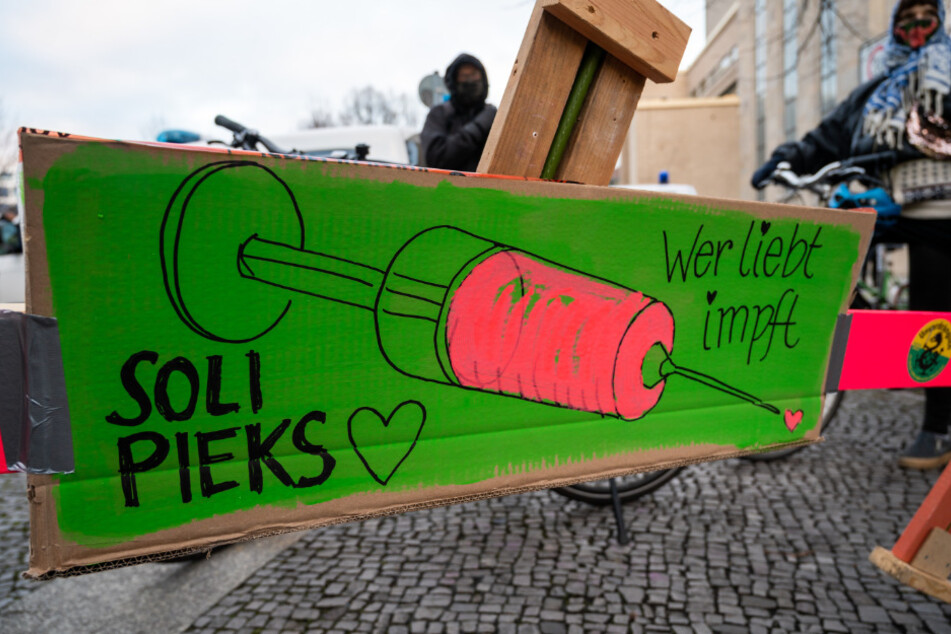 Bei einer Demonstration von Querdenker-Gegnern am Rosa-Luxemburg-Platz steht ein Schild mit der Aufschrift "Soli Pieks - Wer liebt impft".