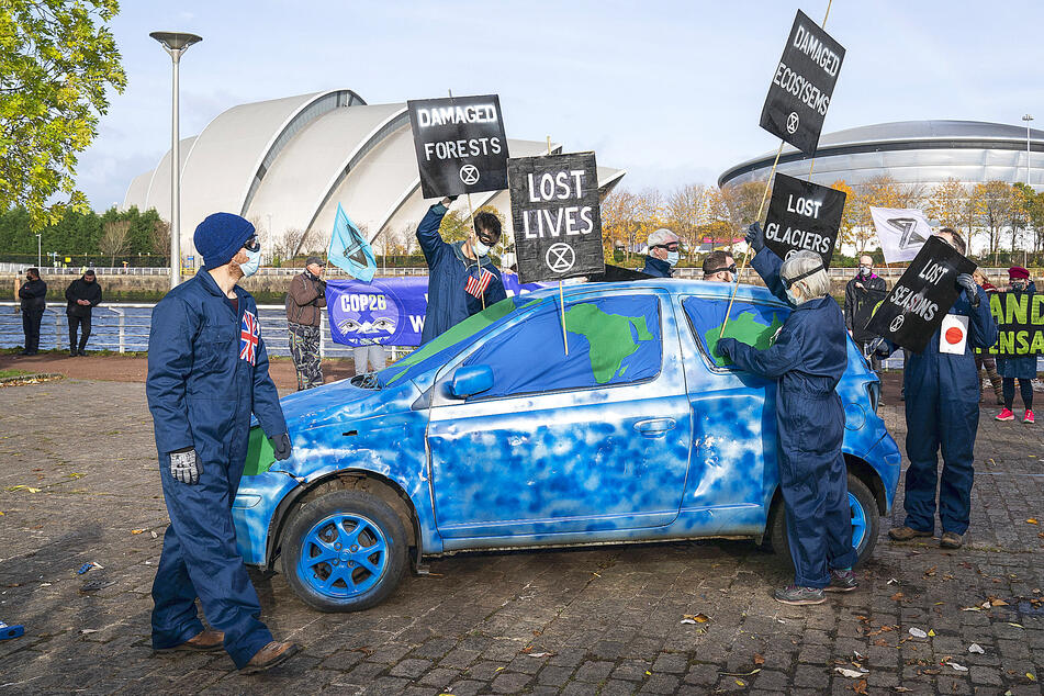 Activists from Extinction Rebellion protest with a car painted to look like a smashed globe across from the COP26 summit campus in Glasgow.