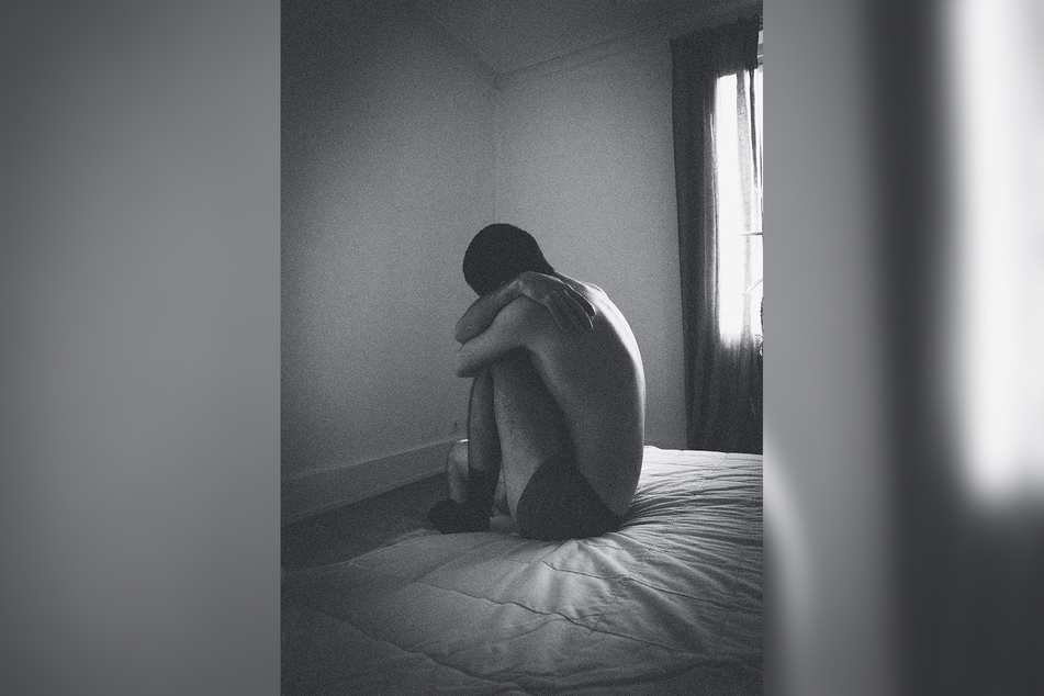 Ein Mann sitzt auf einem Bett in einem tristen Zimmer. (Symbolbild)