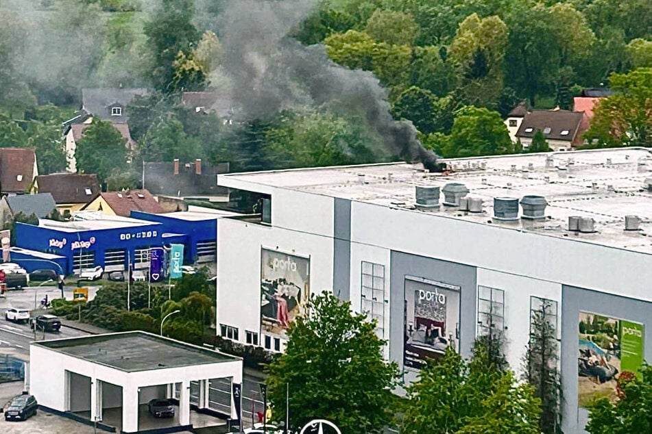 Vom Dach des Möbelhauses steigt eine schwarze Rauchsäule auf.