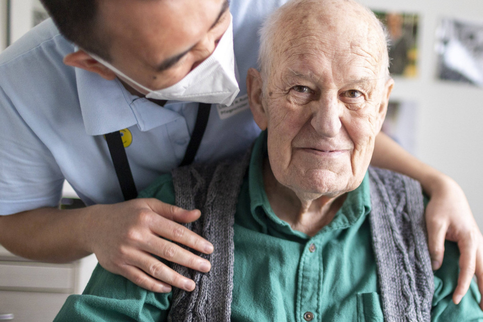 Ein Altenpfleger redet mit dem Bewohner einer Senioren-Residenz.