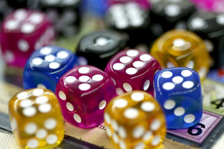 Bunte Würfel liegen bei der Neuheitenvorstellung der Messe "Spiel '19" auf einer Spielkarte.