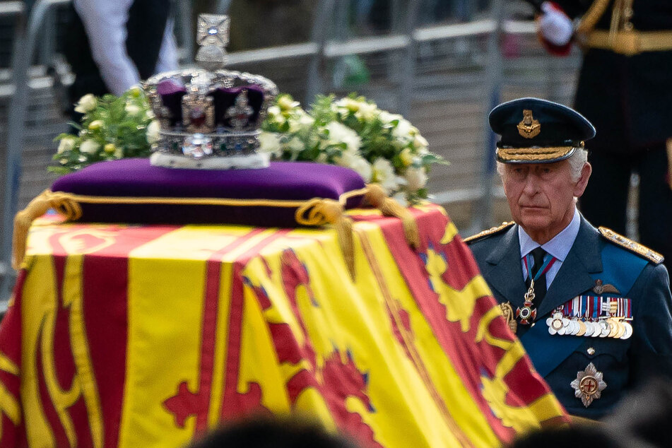 König Charles III. folgt dem Sarg von Königin Elizabeth II., der in die königliche Standarte gehüllt ist und auf dem die kaiserliche Staatskrone thront.