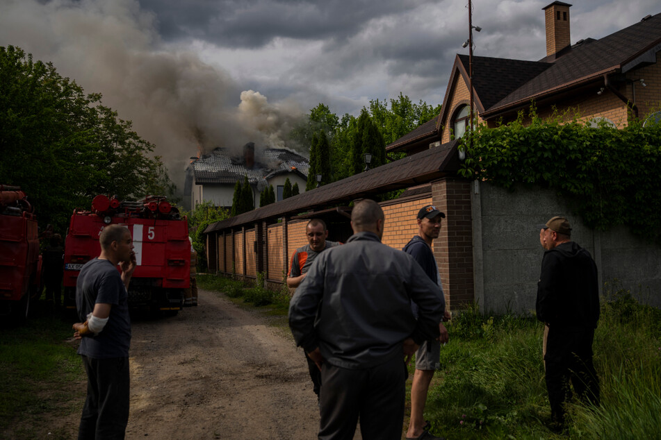 Nachbarn versammeln sich um ein brennendes Haus in Charkiw, das bei einem russischen Angriff mit Streumunition getroffen wurde.