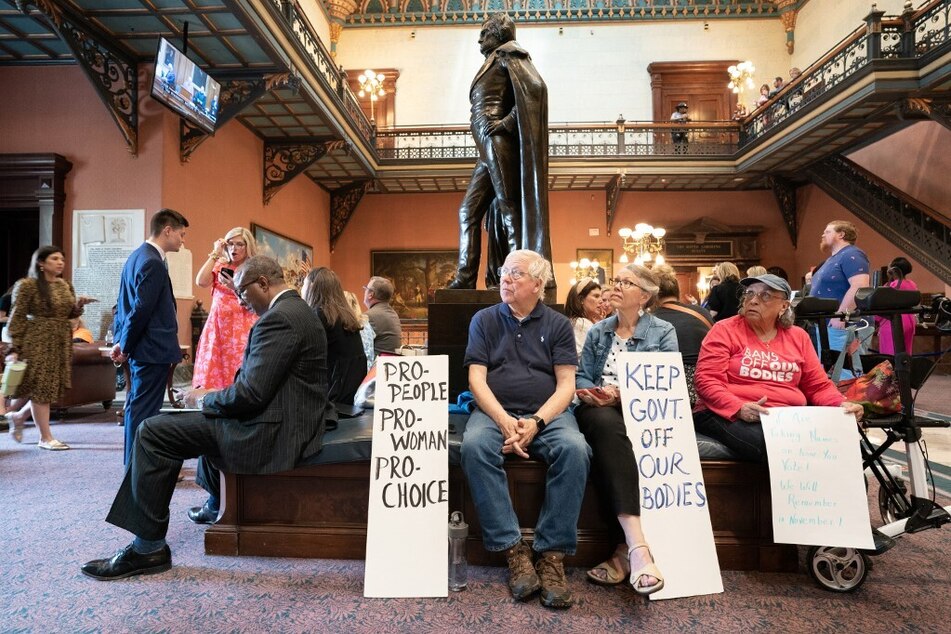 Demonstrators watch a live video feed of state Senate proceedings before the body passed the six-week abortion ban on May 23, 2023.