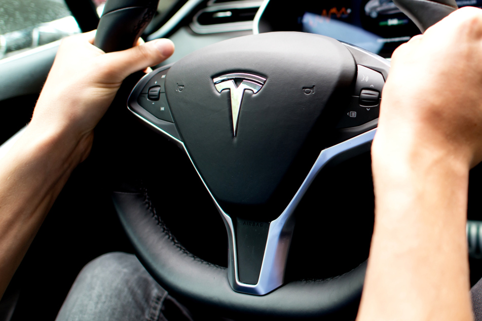 Ein Mann sitzt in einem Tesla Model S am Lenkrad.