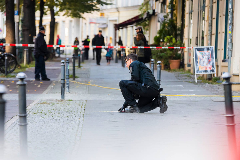 Ein Polizist untersucht Spuren auf dem Gehweg in Brunnenstraße.