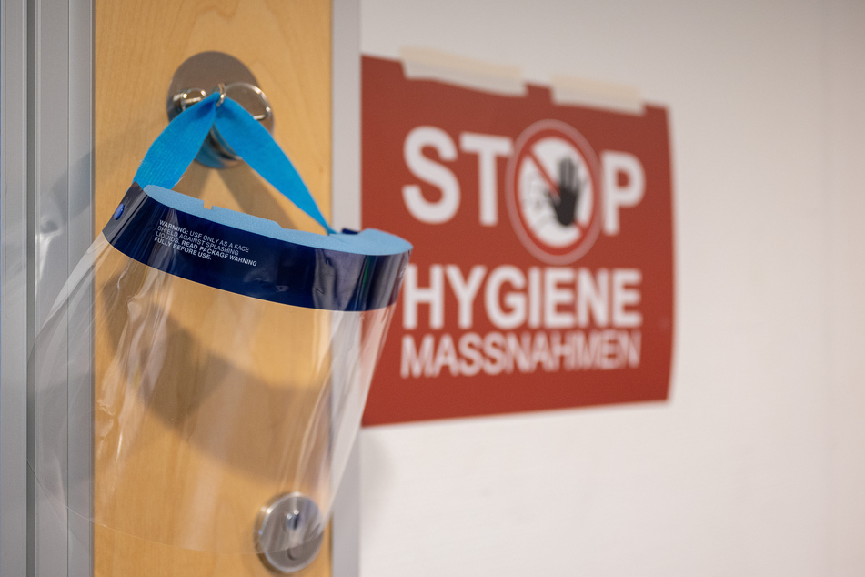 Ein Gesichtsschutz hängt neben einem Schild auf der Intensivstation. Die Hospitalisierungsrate in Hamburg liegt aktuell bei 2,48.
