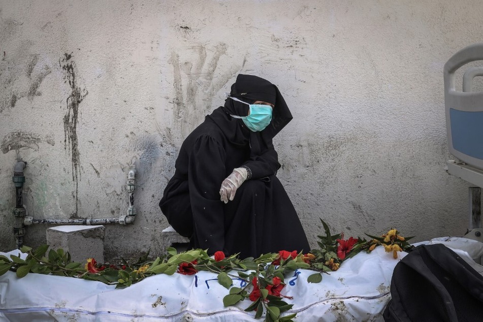 A woman mourns by a body unearthed at Nasser Hospital in Khan Younis in the southern Gaza Strip on April 23, 2024.