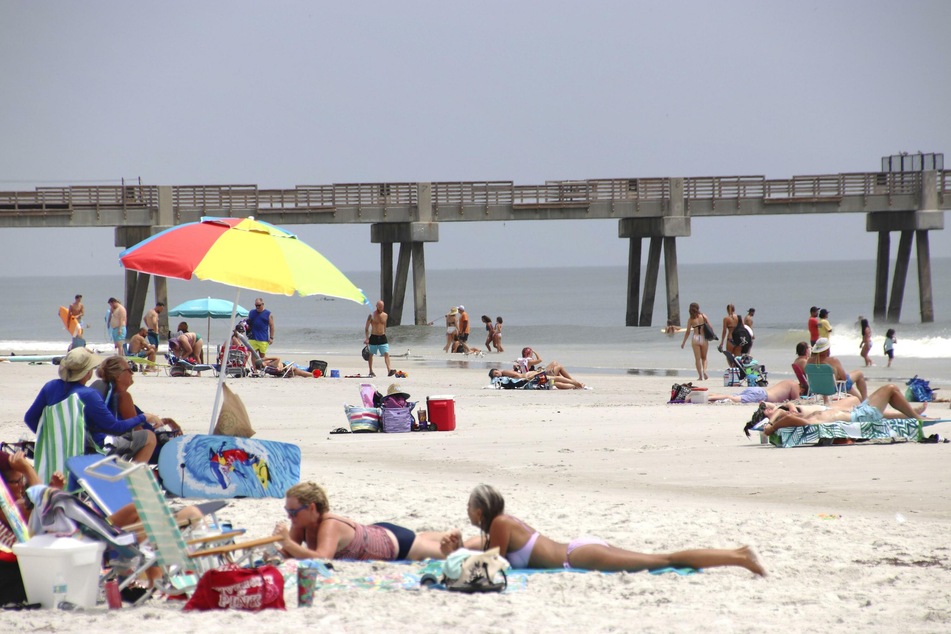 Menschen genießen das warme Wetter an einem Strand. Die Zahl der Corona-Fälle in Florida spitzt sich jedoch zu.