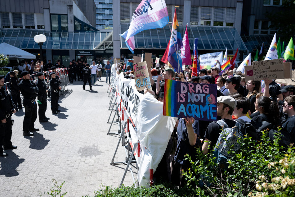 Teilnehmer der Solidaritätsdemo (r.) stehen vor der Stadtteilbibliothek und hinter Absperrungen der Polizei.