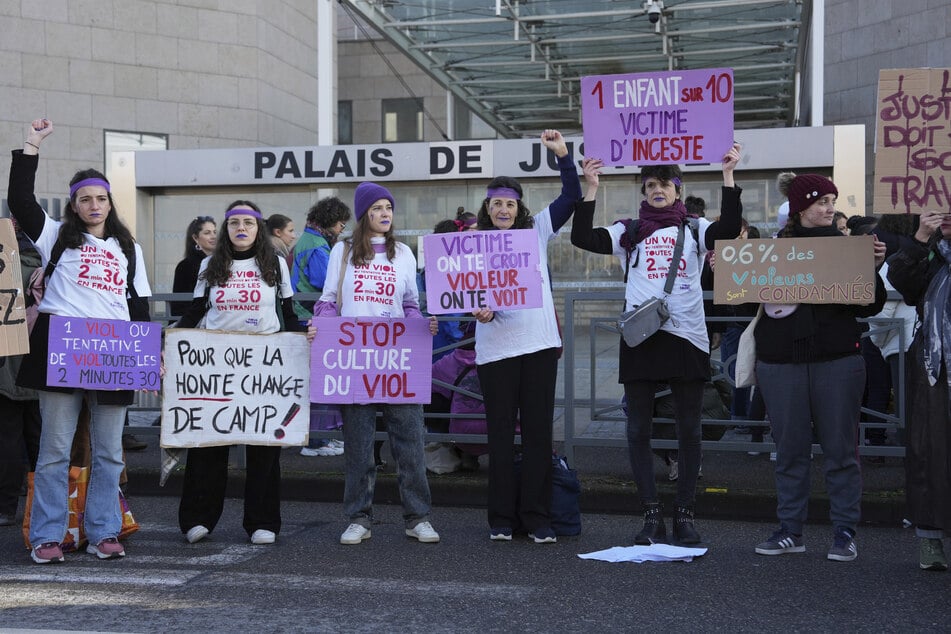 Activists hold placards in front of the Palace of Justice during a demonstration for women's rights.