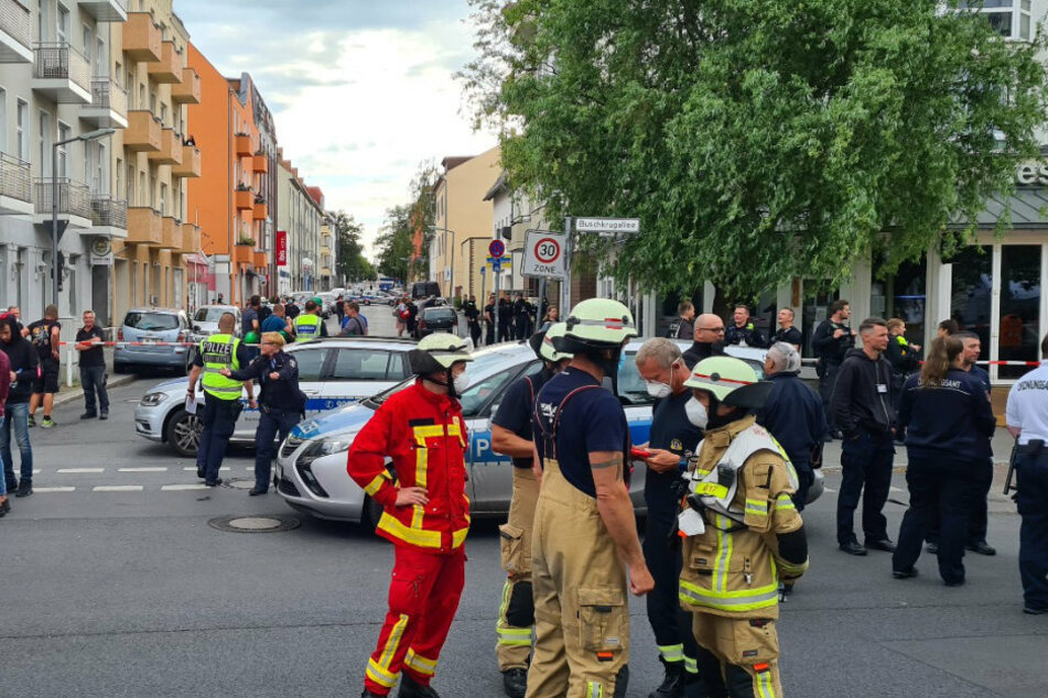 Einsatzkräfte von Polizei und Feuerwehr stehen in der Jahnstraße und Buschkrugallee in Berlin-Neukölln.