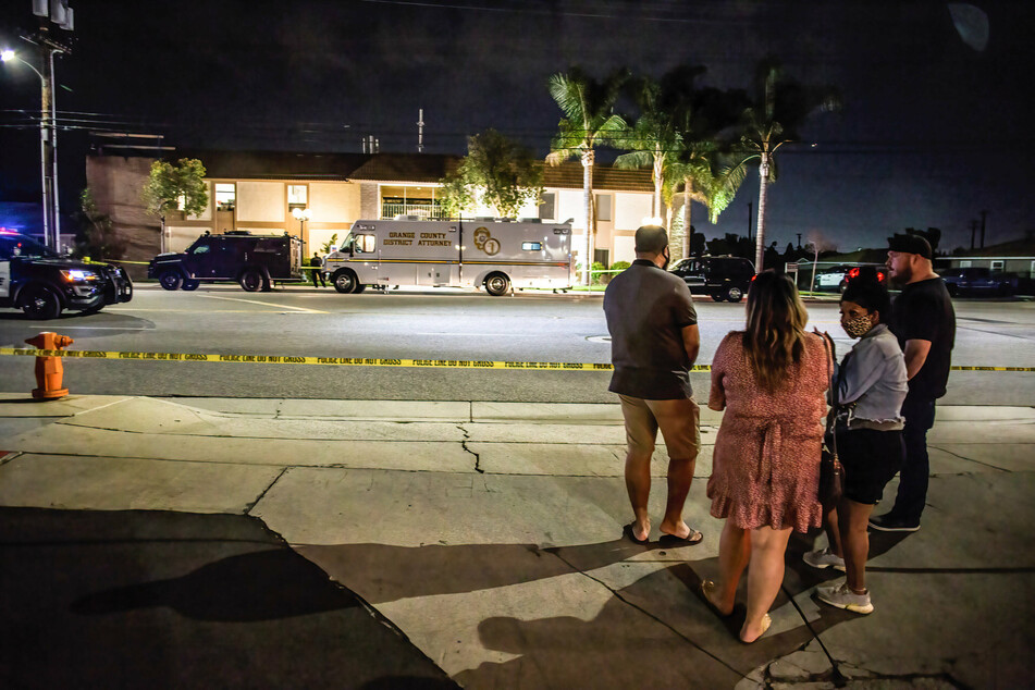 Locals stand and wait for updates across the street from where the shooting occurred.