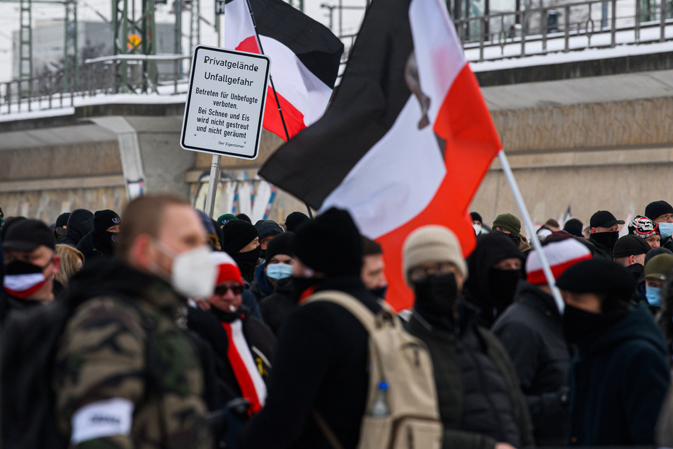 Teilnehmer der rechtsextremen Kundgebung stehen mit schwarzrotweißen Flaggen vor dem Hauptbahnhof.