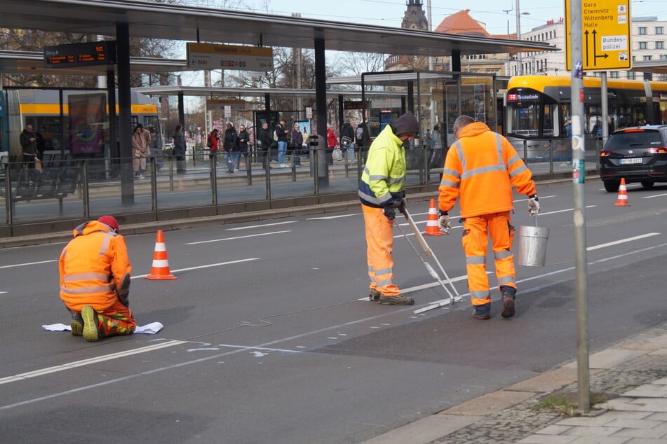 Drei Arbeiter führen die Markierungsarbeiten vor dem Leipziger Hauptbahnhof aus.