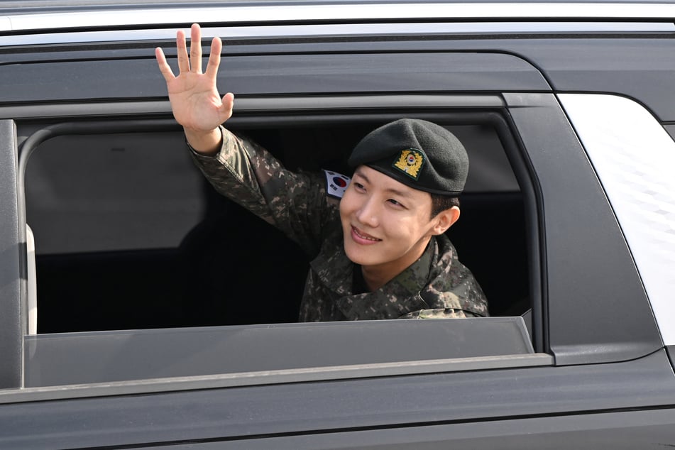 BTS member J-hope waves to fans after his discharge from mandatory military service outside a base in Wonju, South Korea, on October 17, 2024.