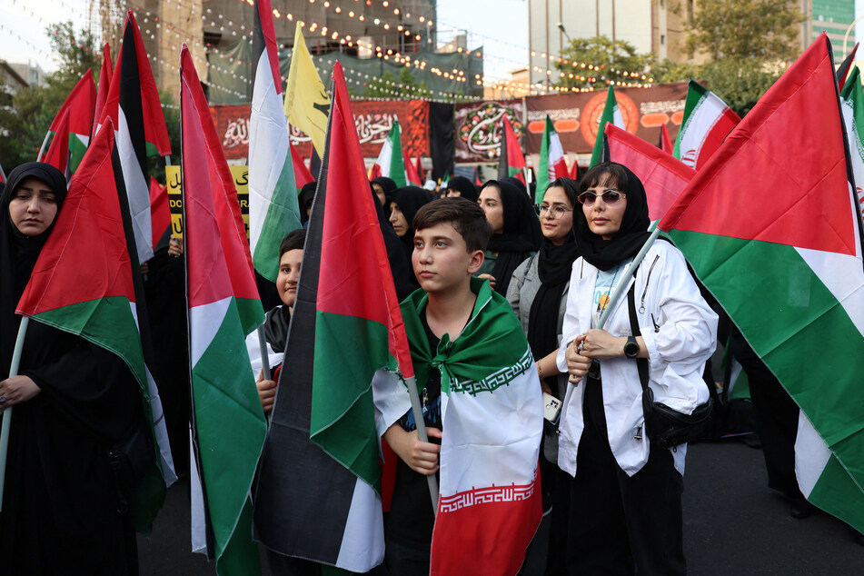 Iranians wave Palestinian flags during a protest against Israel's assault at Palestine square in the Iranian capital of Tehran.