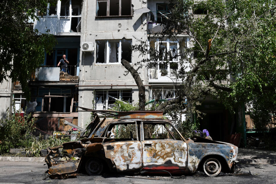Ein zerstörtes Auto steht vor einem Wohnhaus, das bei einem nächtlichen Raketeneinschlag beschädigt wurde.