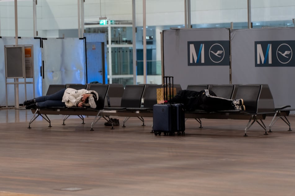 Gestrandete Reisende haben sich auf Sitzbänken am Münchner Flughafen schlafen gelegt.