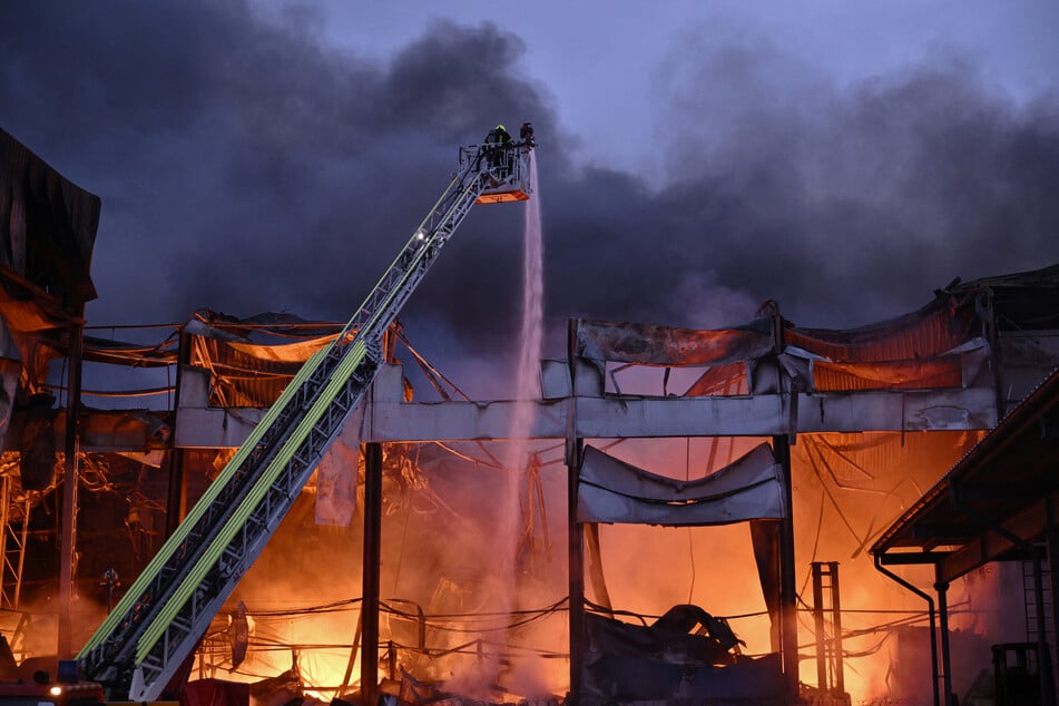 Ukrainian firefighters extinguish a blaze at the site of a food warehouse following a Russian missile strike in Kyiv early on October 25, 2025.