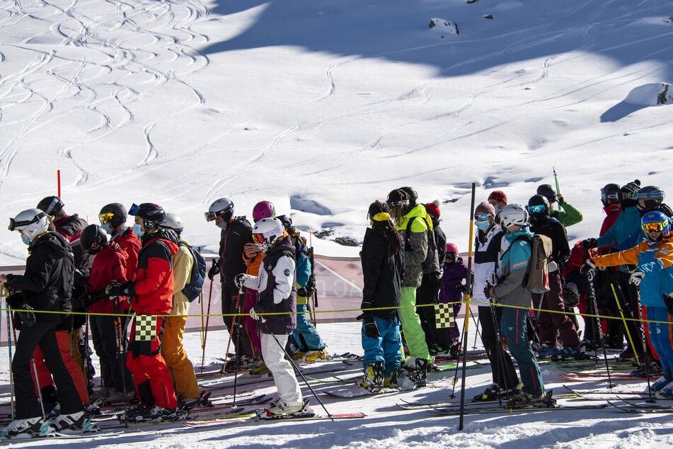 Skifahrer mit Gesichtsmasken stehen am Eröffnungstag des Skigebiets Verbier in den Schweizer Alpen in einer Schlange für den Sessellift an.