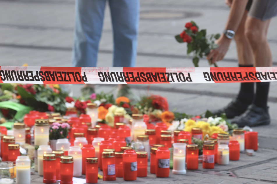 Blumen werden vor dem abgesperrten Kaufhaus, in dem der 24-Jährige Menschen mit einem Messer attackiert hatte, niedergelegt.