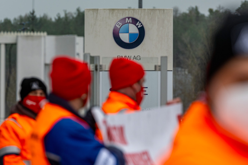 Gewerkschaftsmitglieder stehen vor dem Eingang eines BMW-Werks.