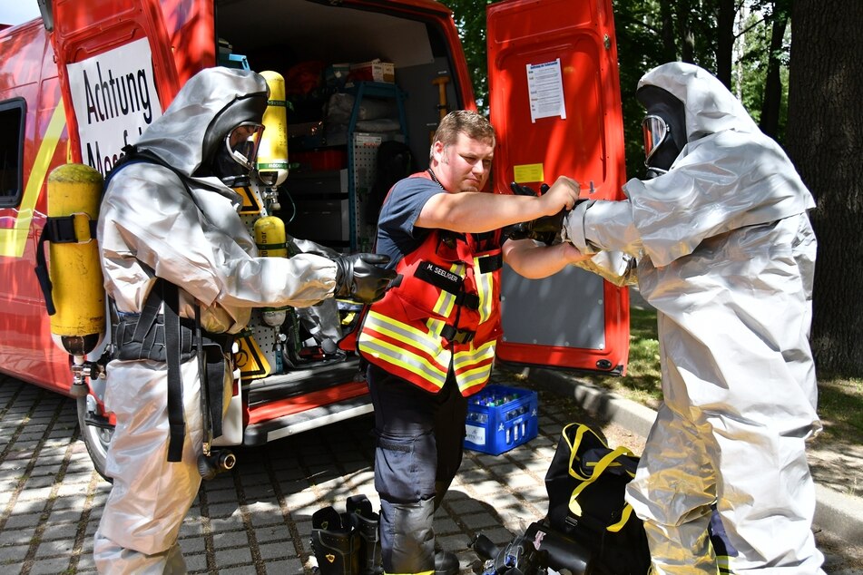 Schutz muss sein! Ein Kollege hilft den Einsatzkräften mit ihren Anzügen.