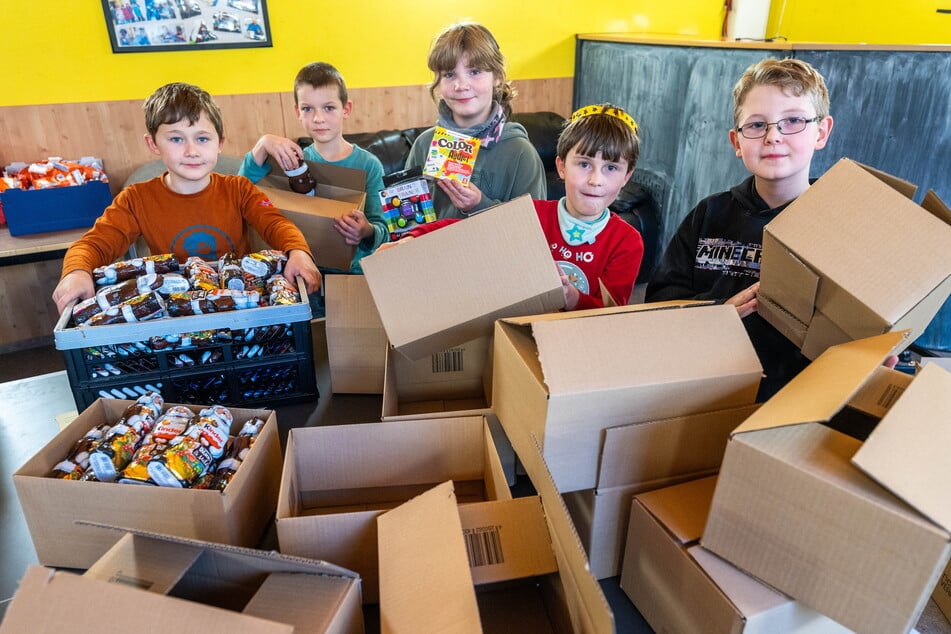 Joel (7, v.l.), Rafael (9), Lina (9), Georg (8) und Lui (9) von der Grundschule Harthau verpacken Weihnachtspäckchen für andere Kinder. In den Päckchen befindet sich Süßigkeiten und Spiele im Wert von jeweils 15 Euro.