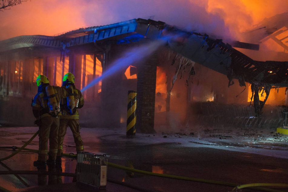 Die Feuerwehrleute bekämpfen die Flammen von außen, nachdem das Dach eingestürzt ist.
