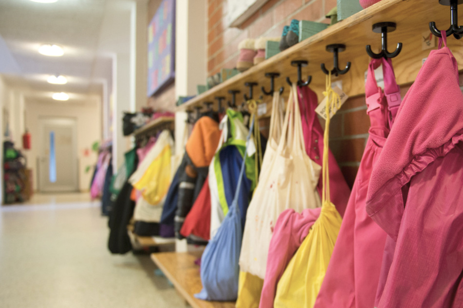 Jacken und Turnbeutel sind in einer Kindertagesstätte an einer Garderobe zu sehen.