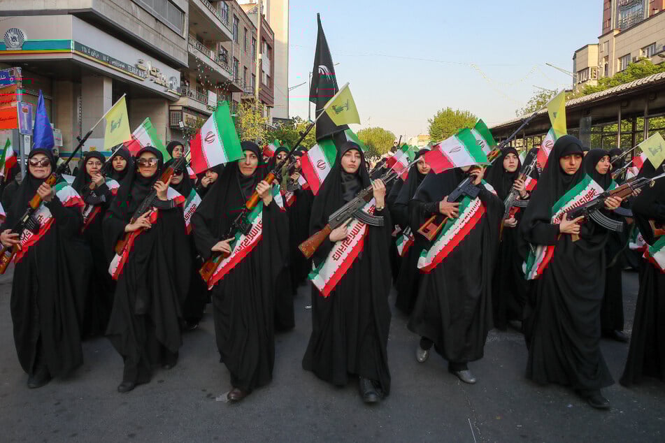 Iranische Frauen halten Waffen in der Hand, als sie an einer Kundgebung in Teheran teilnehmen, um den im Krieg getöteten Frauen zu gedenken.