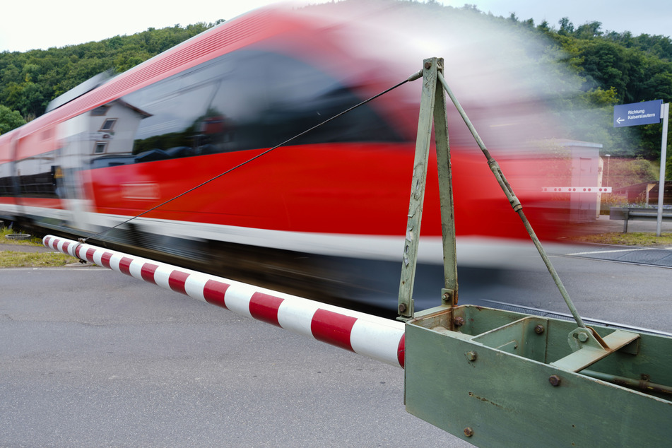 Ein Zug überquert an einem Bahnübergang bei geschlossener Bahnschranke. (Symbolbild)