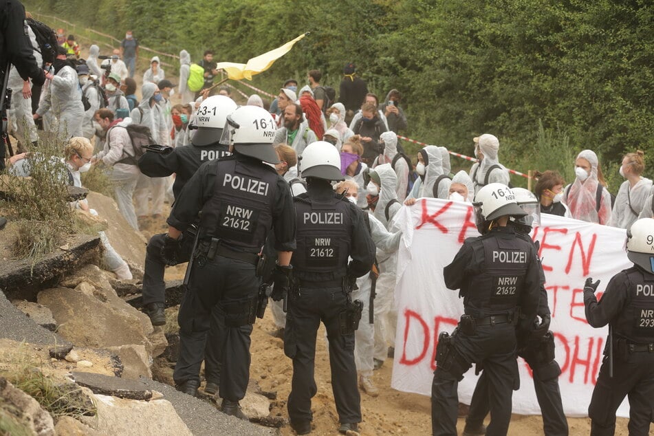 Keyenberg: Umweltaktivisten im weissen Overalls klettern über ein Wall um in dem Tagebau Garzweiler einzudringen und werden von der Polizei zuruckgewiesen.