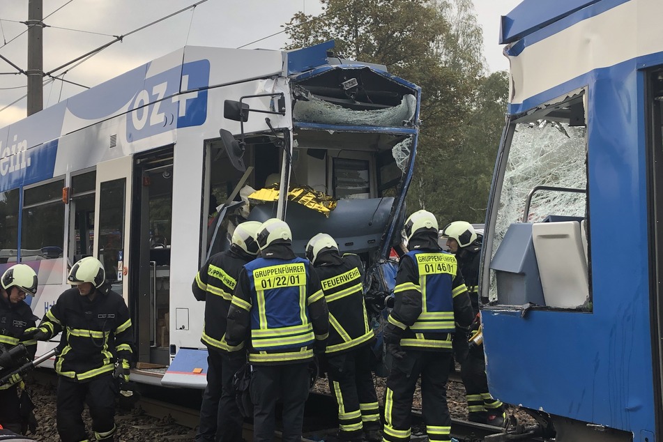Einsatzkräfte der Feuerwehr arbeiten nach der Straßenbahnkollision am Unfallort.