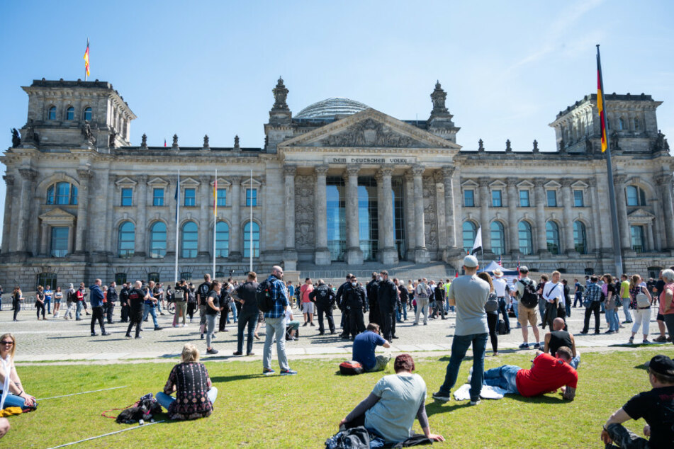 Menschen nehmen an einer Demonstration vor dem Reichstagsgebäude teil.