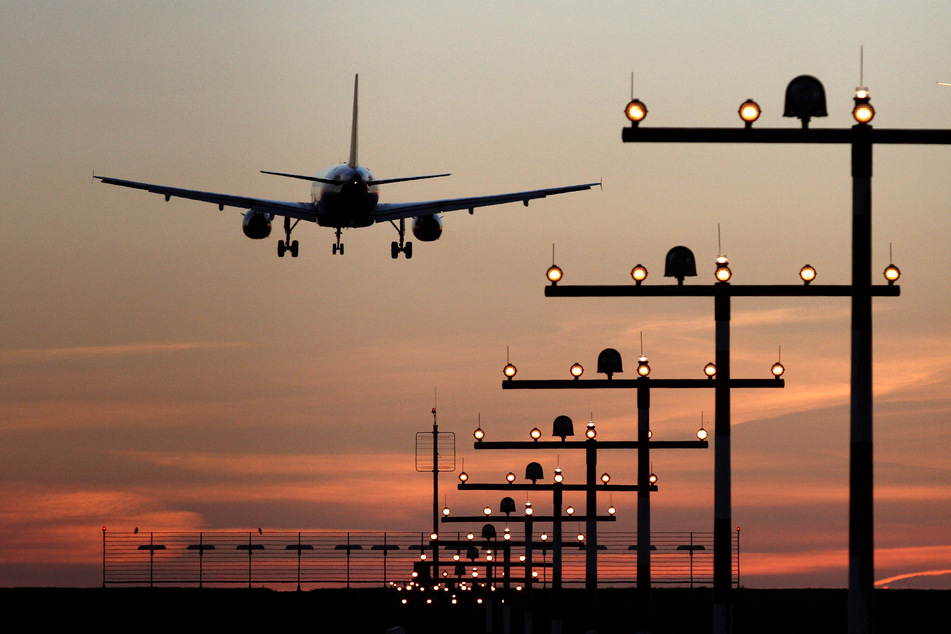 Ein Flugzeug ist während des Sonnenuntergangs im Landeanflug auf den Flughafen Düsseldorf.